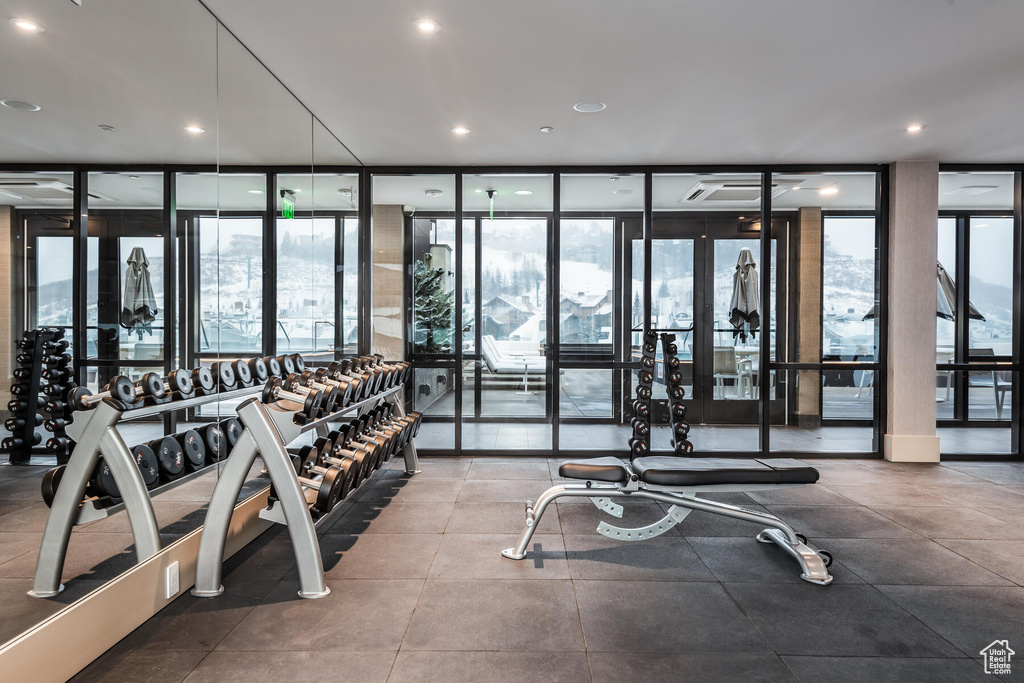 Workout area with a wall of windows, light tile floors, and french doors