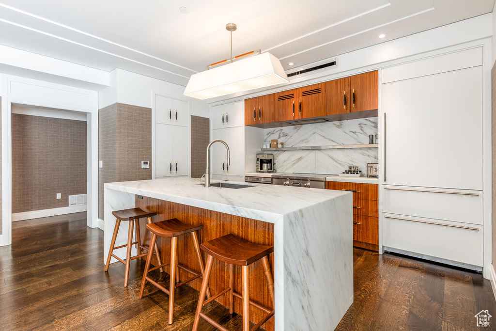 Kitchen featuring pendant lighting, dark hardwood / wood-style flooring, sink, and backsplash