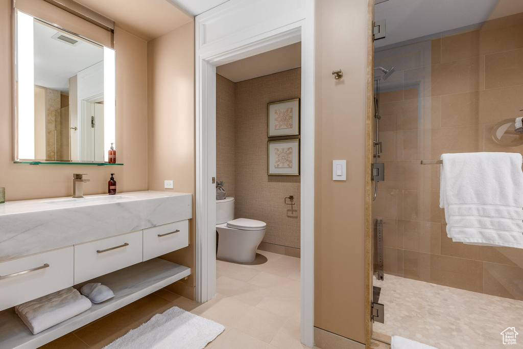 Bathroom featuring a shower with door, vanity, tile flooring, and toilet