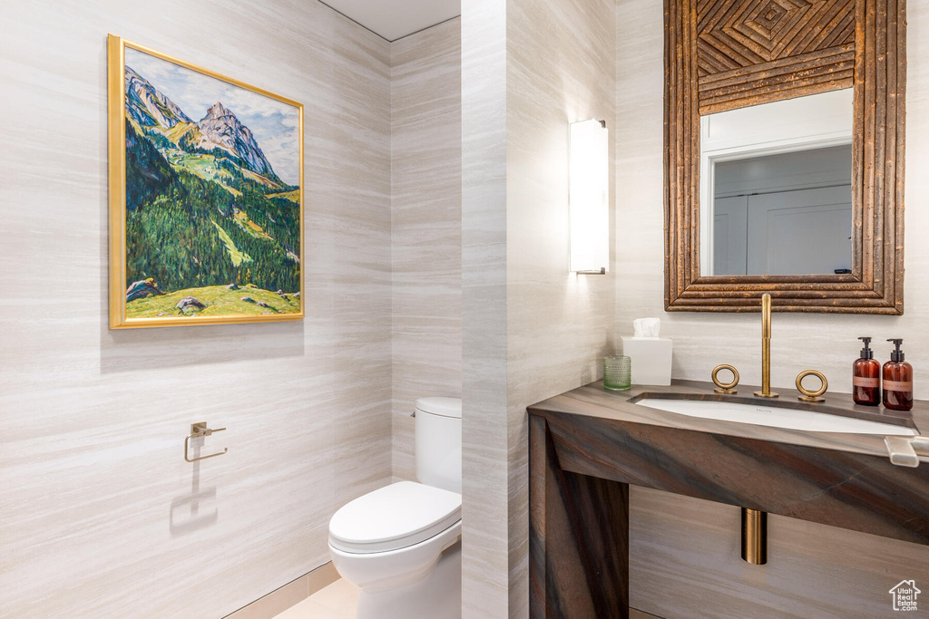 Bathroom featuring vanity, tile walls, and toilet