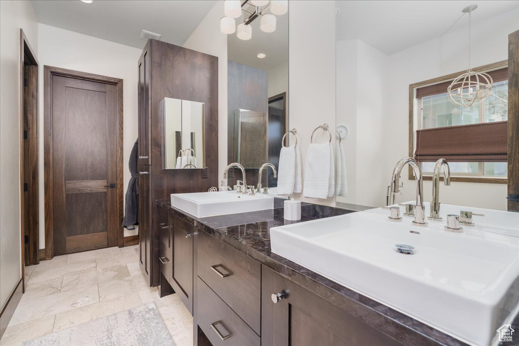Bathroom featuring tile floors, a notable chandelier, and double sink vanity