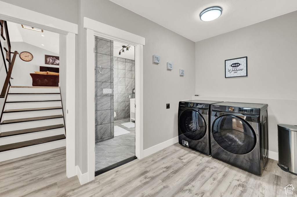 Laundry area with light hardwood / wood-style floors and washing machine and dryer