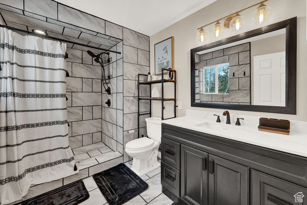 Bathroom with a shower with curtain, vanity, tile flooring, and toilet