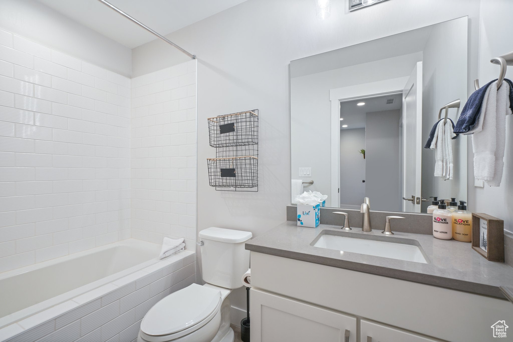 Full bathroom featuring large vanity, tiled shower / bath combo, and toilet
