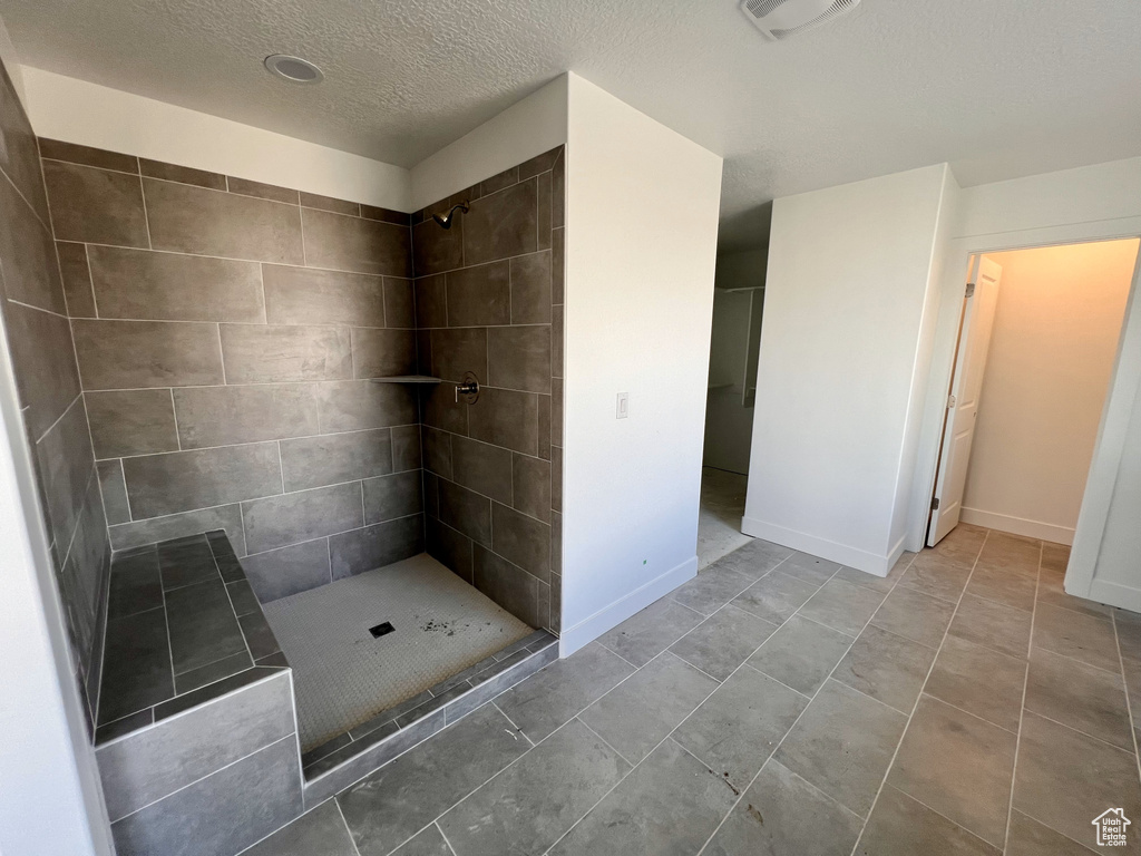 Bathroom featuring tiled shower, tile flooring, and a textured ceiling