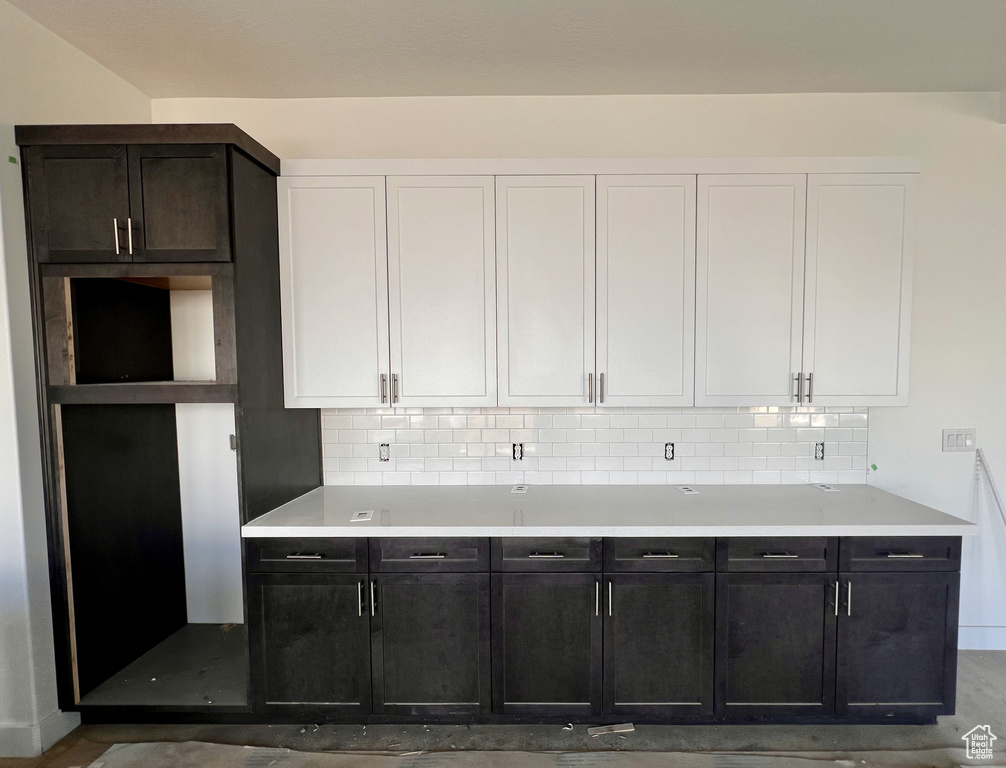 Kitchen with backsplash, dark brown cabinets, and white cabinetry