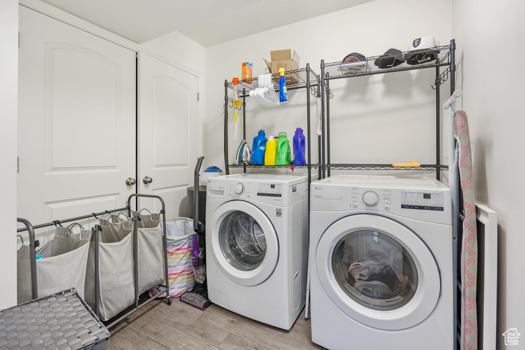 Laundry area with washer and dryer and light hardwood / wood-style floors