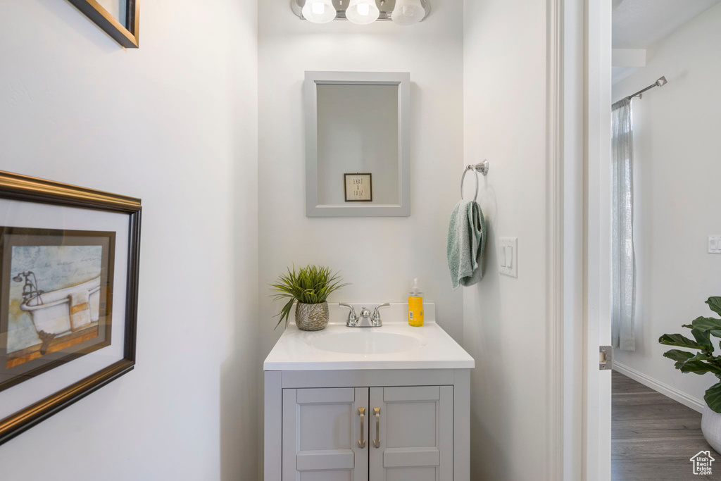 Bathroom with a notable chandelier, hardwood / wood-style floors, and vanity with extensive cabinet space