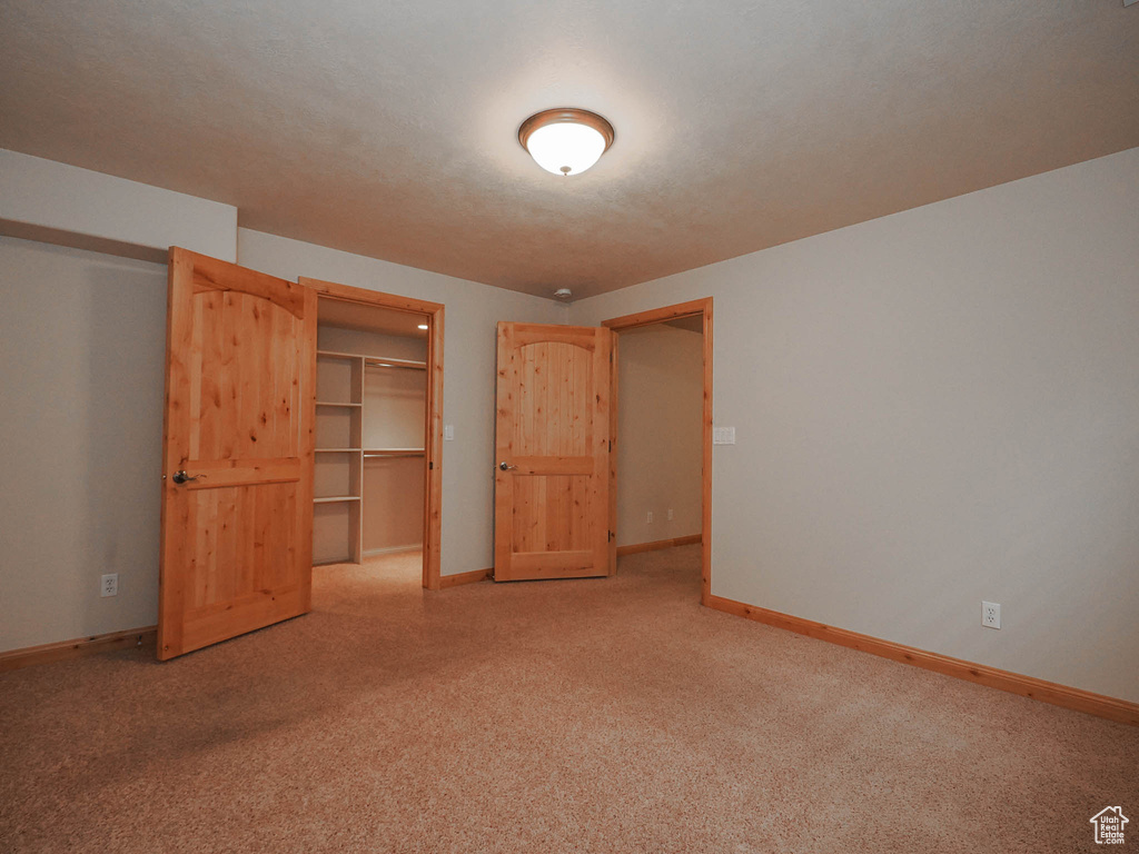 Unfurnished bedroom featuring a closet, a spacious closet, and light colored carpet