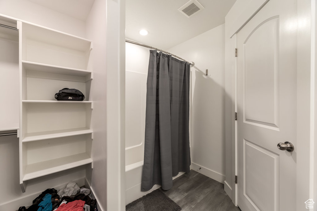Bathroom with hardwood / wood-style floors and shower / bath combination with curtain