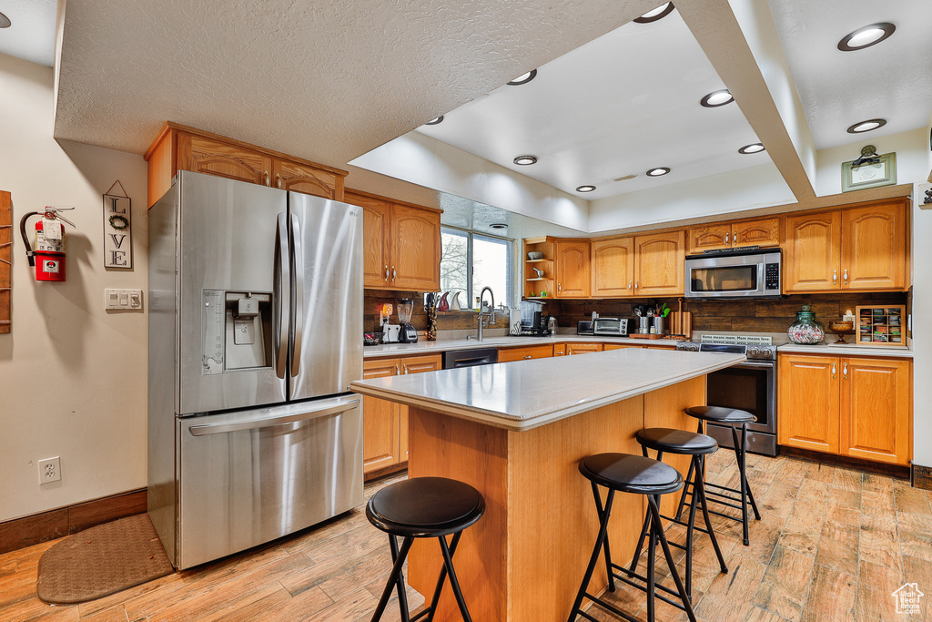Kitchen featuring a breakfast bar area, stainless steel appliances, light wood-type flooring, and a center island