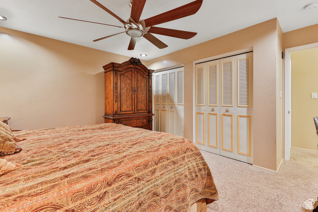 Carpeted bedroom featuring multiple closets and ceiling fan