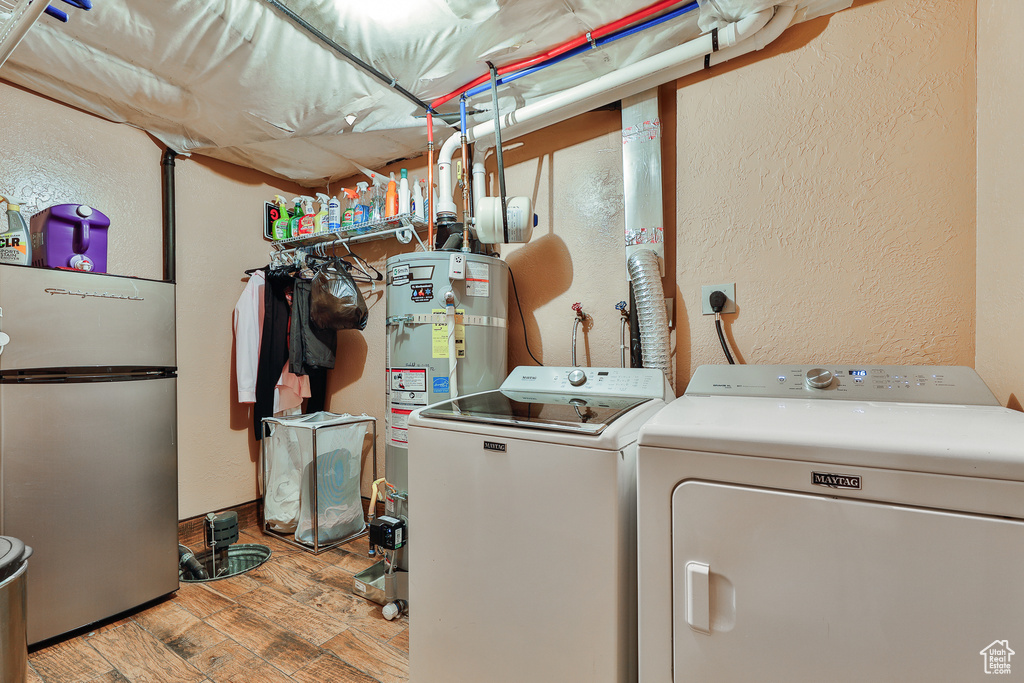 Clothes washing area with electric dryer hookup, light wood-type flooring, separate washer and dryer, and strapped water heater