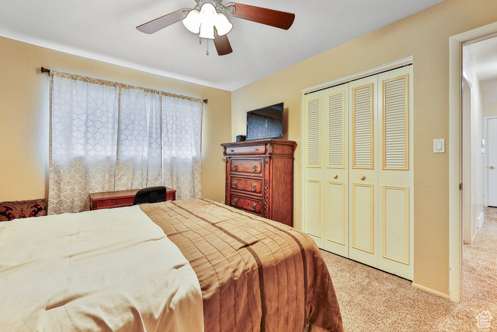 Bedroom with light carpet, a closet, and ceiling fan
