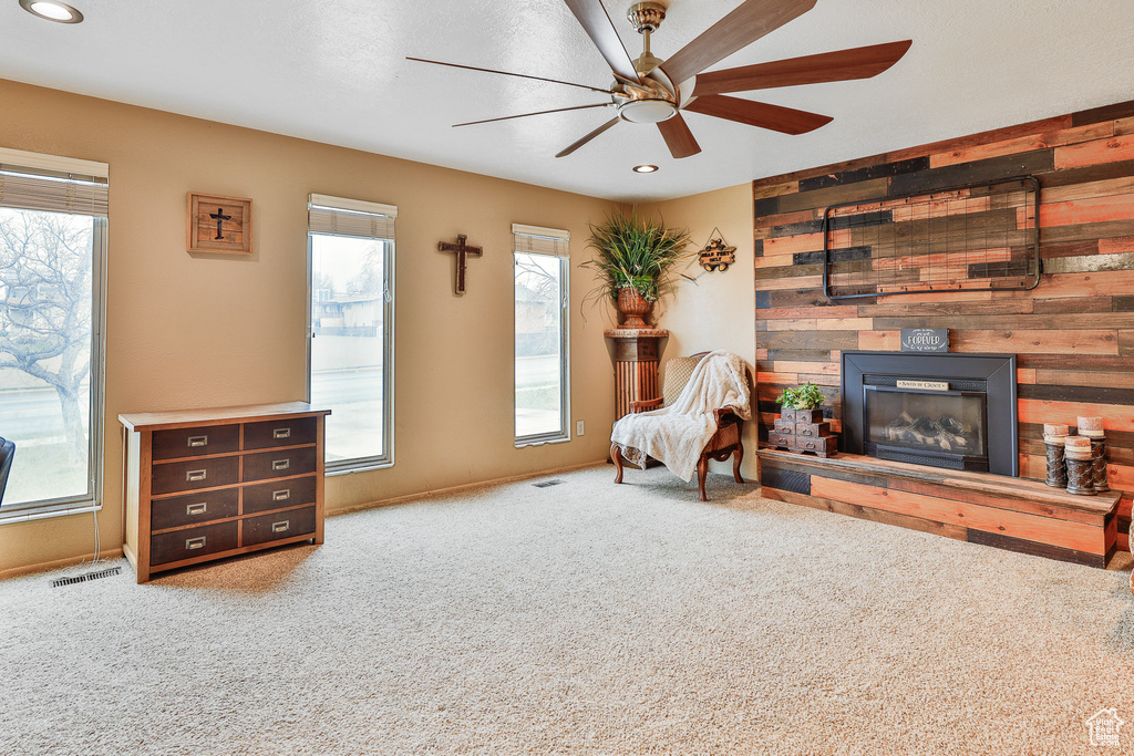 Living area with light colored carpet, ceiling fan, and wooden walls
