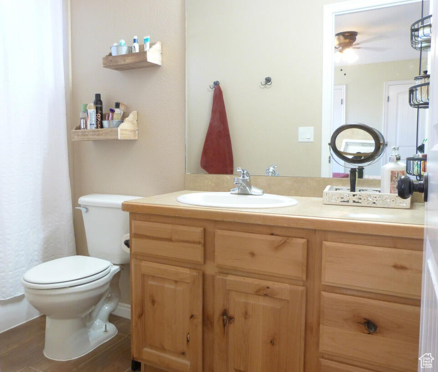 Bathroom featuring hardwood / wood-style flooring, ceiling fan, oversized vanity, and toilet