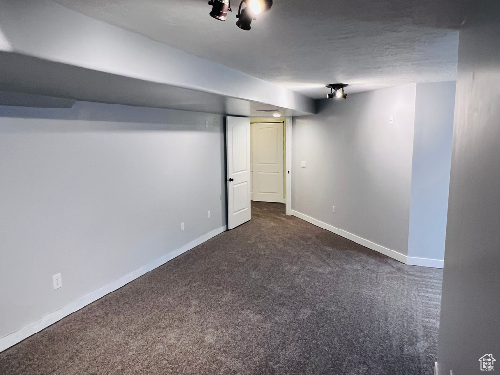 Basement with dark colored carpet and a textured ceiling