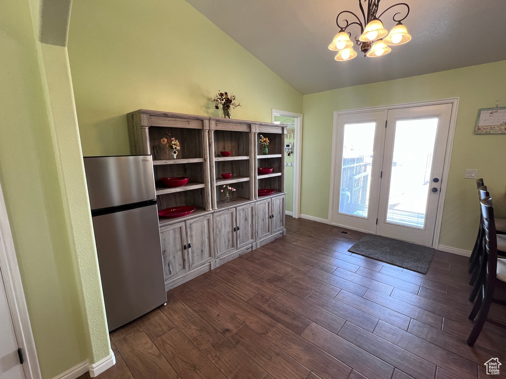 Kitchen featuring vaulted ceiling, stainless steel fridge, dark hardwood / wood-style flooring, decorative light fixtures, and a chandelier