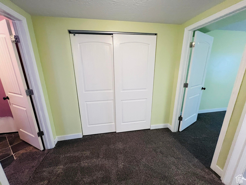 Unfurnished bedroom with a closet and dark tile floors