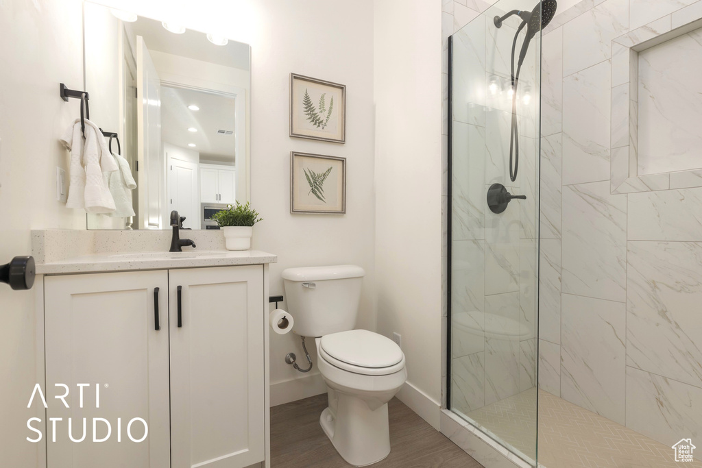 Bathroom with large vanity, hardwood / wood-style floors, a shower with door, and toilet