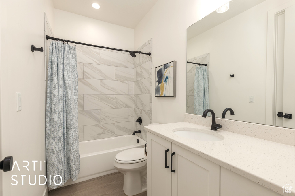 Full bathroom with toilet, hardwood / wood-style floors, shower / tub combo, and oversized vanity