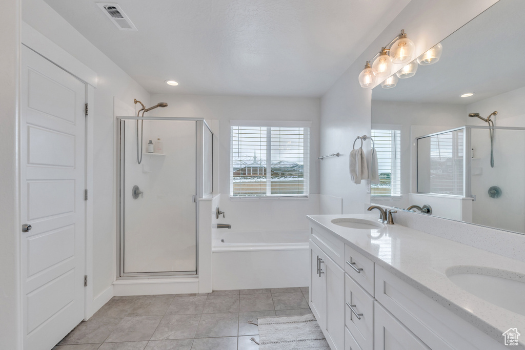 Bathroom featuring shower with separate bathtub, double sink vanity, and tile flooring