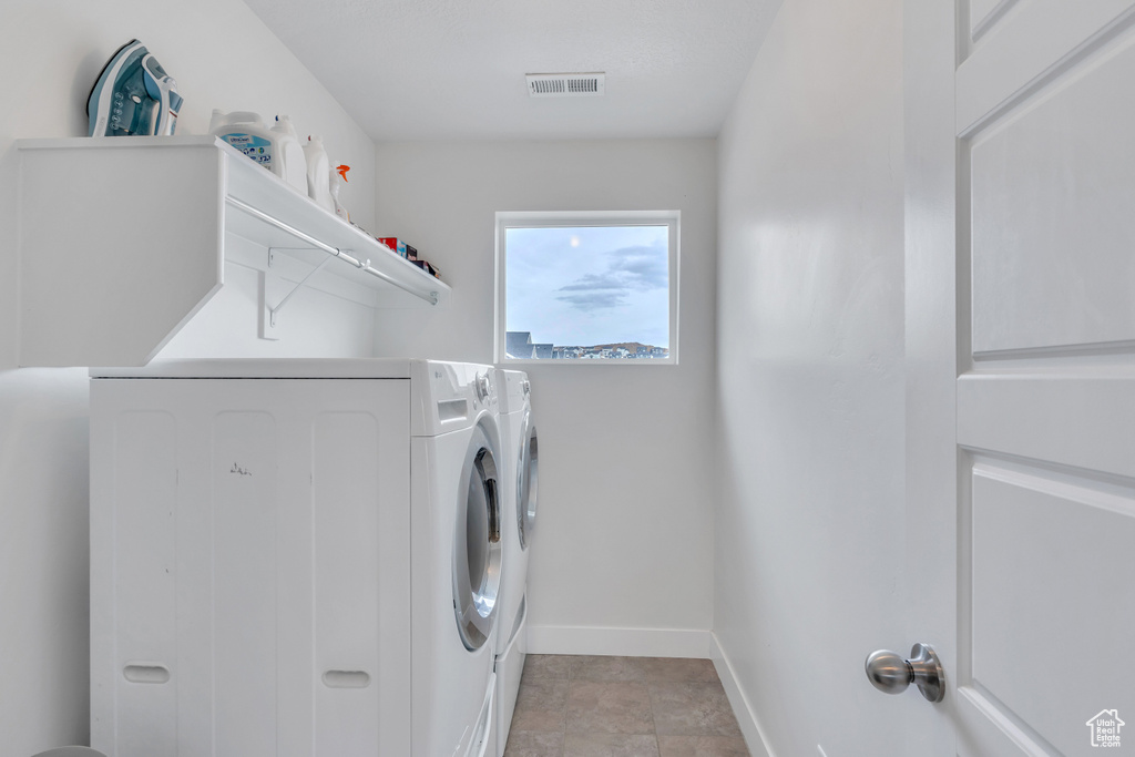 Laundry room with light tile floors and independent washer and dryer