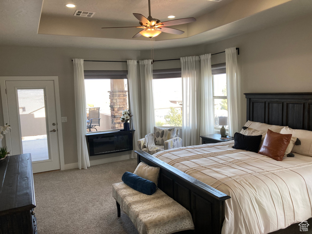 Carpeted bedroom featuring a tray ceiling and ceiling fan