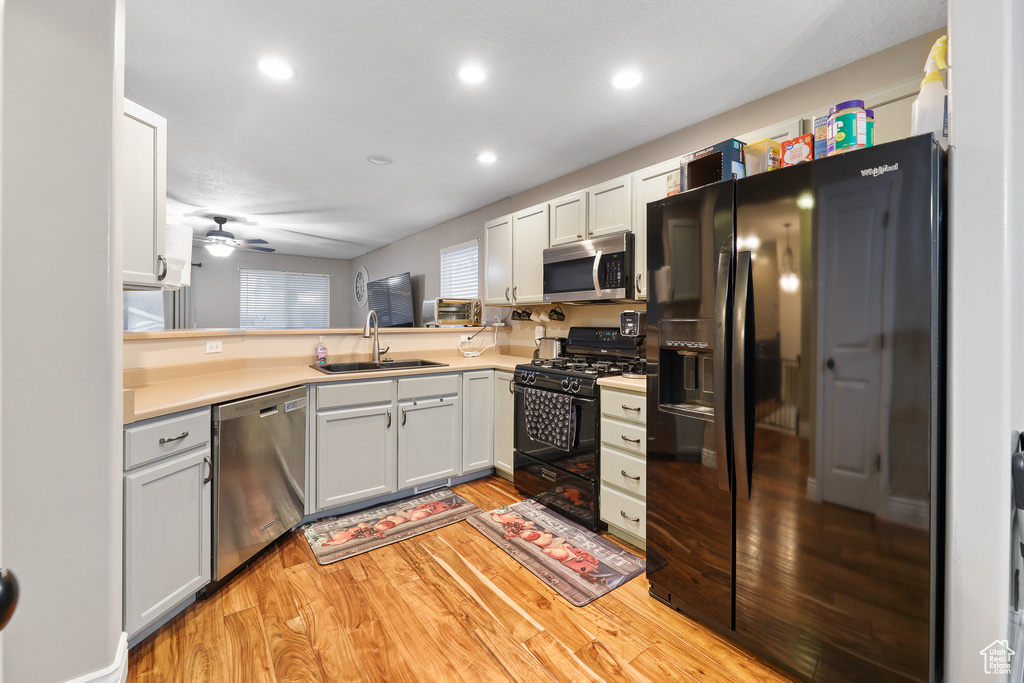 Kitchen featuring white cabinetry, light hardwood / wood-style flooring, ceiling fan, and black appliances