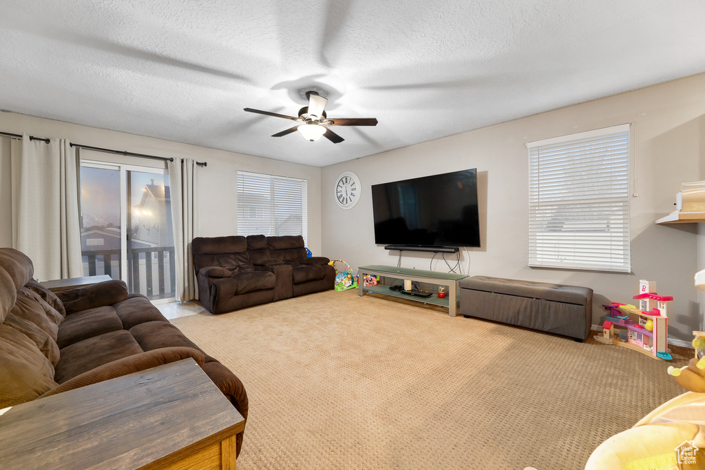 Living room with ceiling fan, light colored carpet, and a textured ceiling