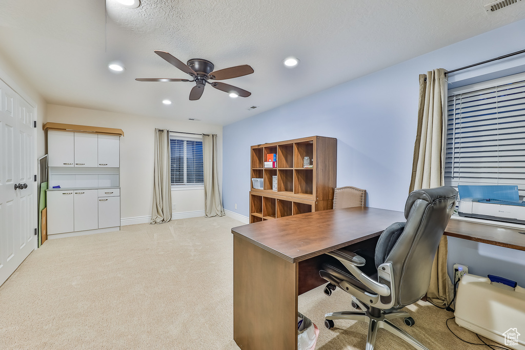 Carpeted office space with ceiling fan and a textured ceiling