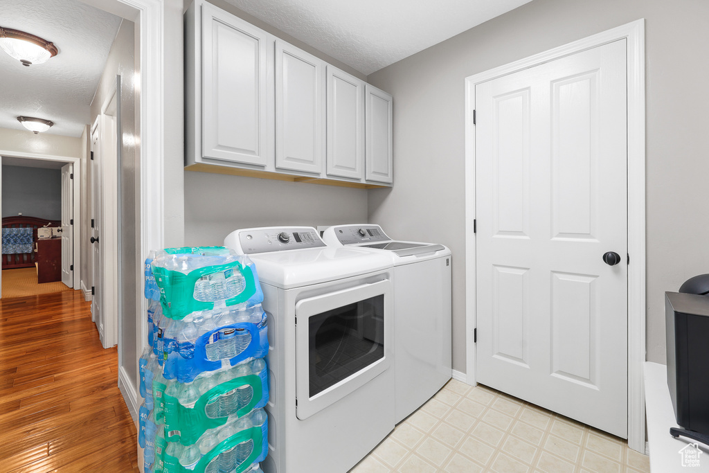 Laundry area with cabinets, independent washer and dryer, and light tile floors