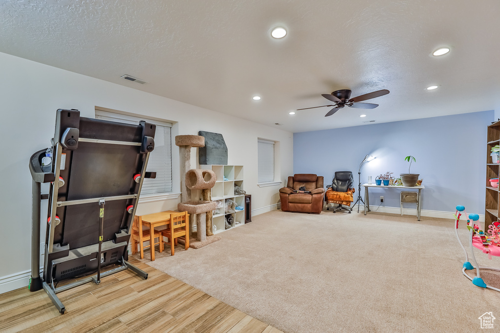 Rec room featuring light hardwood / wood-style floors, ceiling fan, and a textured ceiling