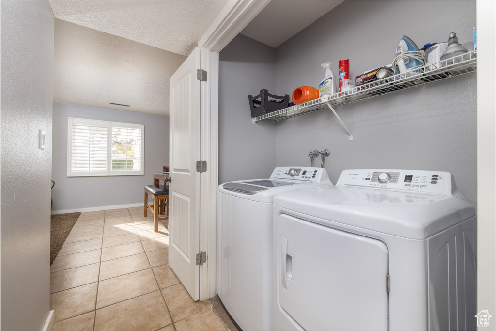 Clothes washing area with hookup for a washing machine, separate washer and dryer, and light tile floors