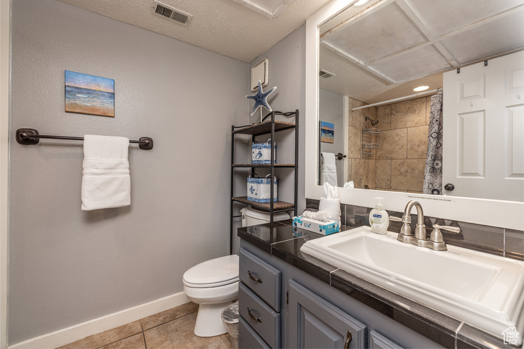 Bathroom featuring vanity, toilet, a textured ceiling, and tile flooring