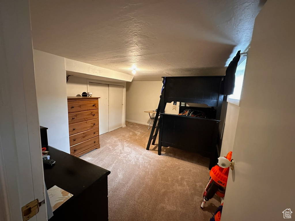 Bedroom with a closet, light colored carpet, and a textured ceiling