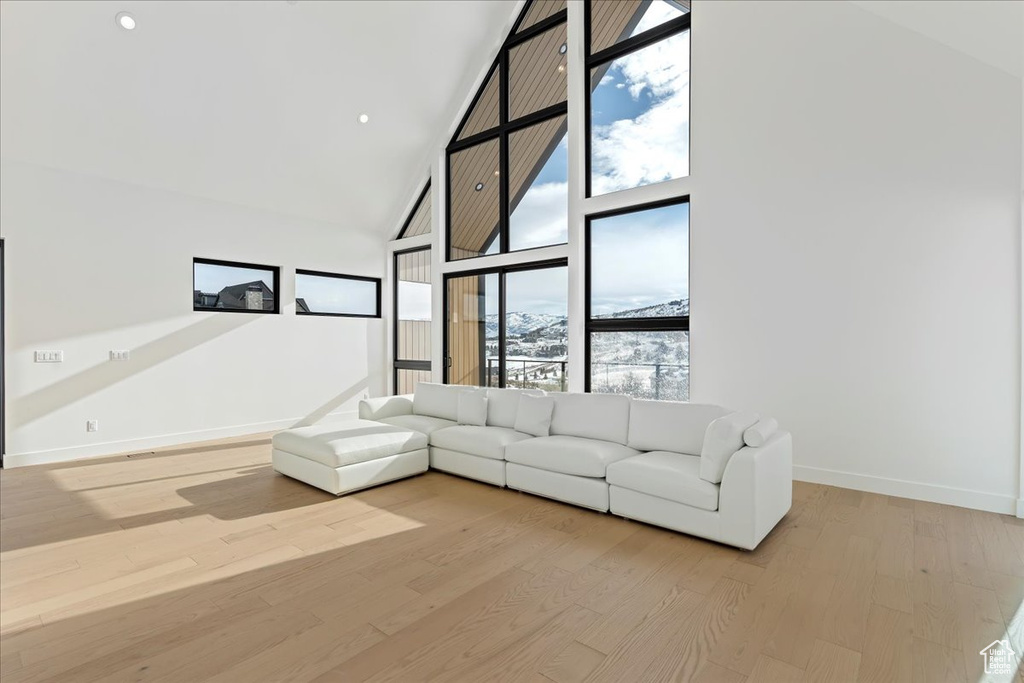 Unfurnished living room featuring light hardwood / wood-style flooring, a wall of windows, and a high ceiling
