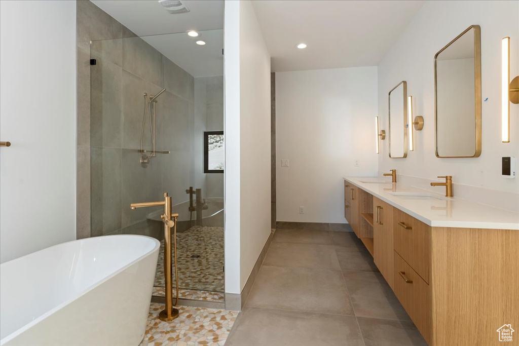 Bathroom with dual vanity, tile floors, and shower with separate bathtub