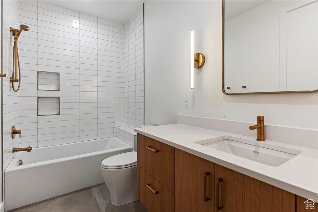 Full bathroom featuring toilet, vanity with extensive cabinet space, tiled shower / bath, and tile flooring