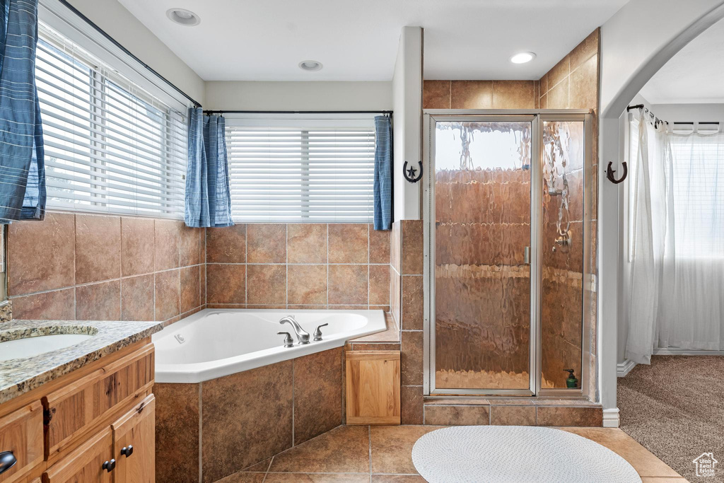 Bathroom featuring plenty of natural light, vanity, shower with separate bathtub, and tile flooring