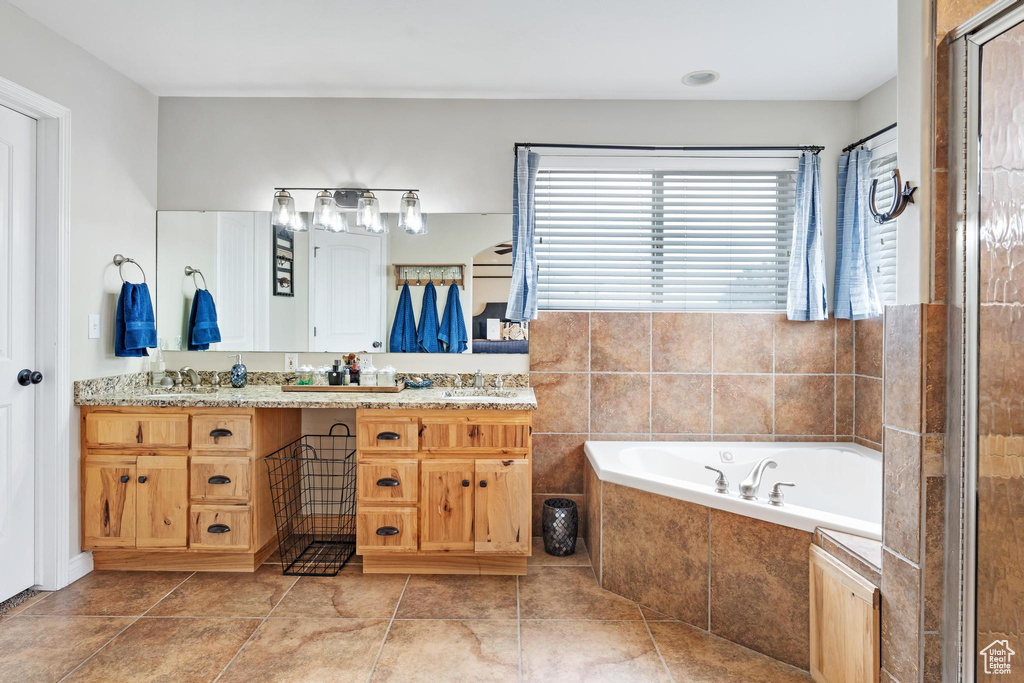 Bathroom featuring vanity, tiled bath, and tile flooring