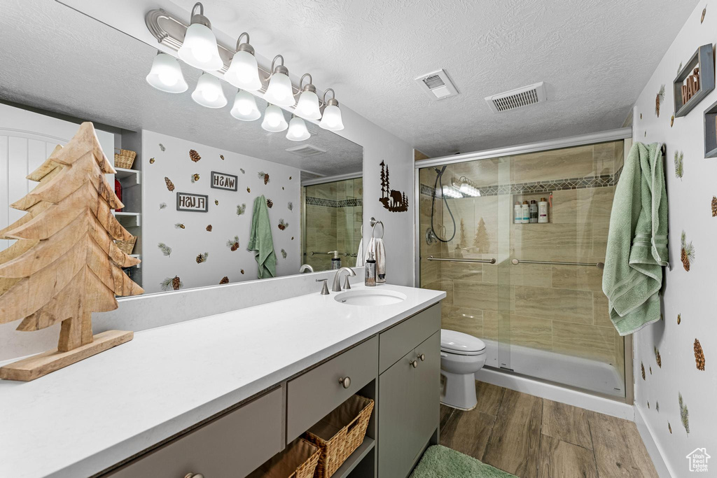 Bathroom with a textured ceiling, toilet, walk in shower, hardwood / wood-style flooring, and large vanity