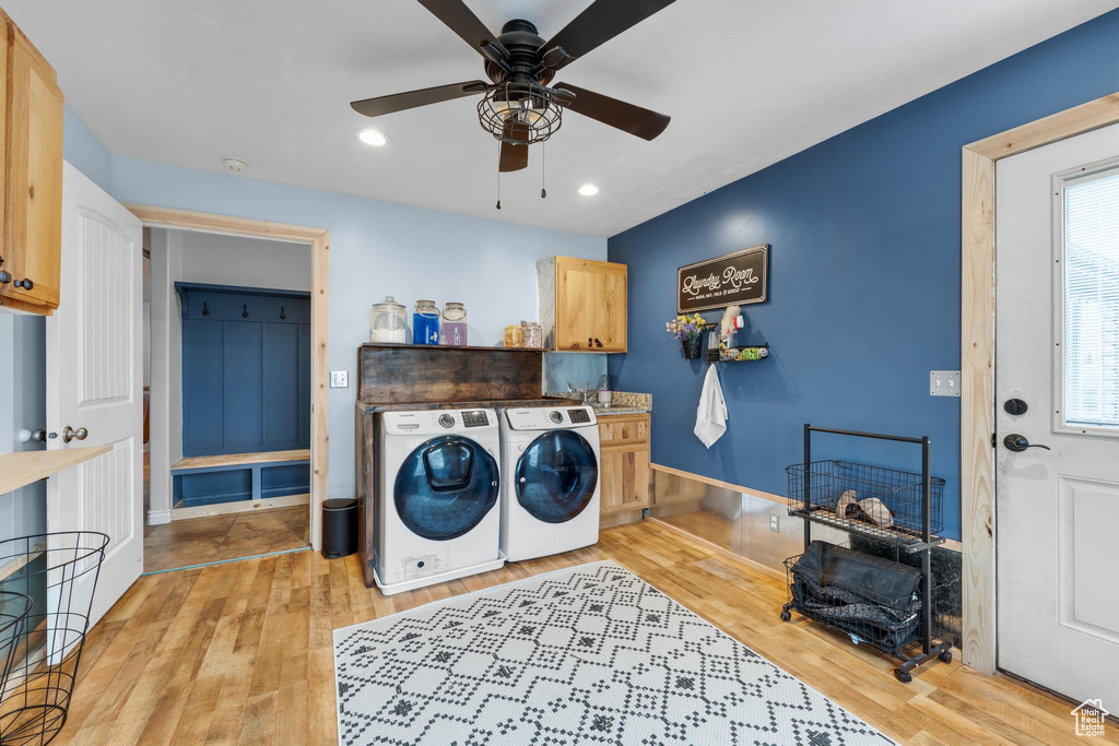 Washroom with washing machine and clothes dryer, light hardwood / wood-style floors, ceiling fan, and cabinets