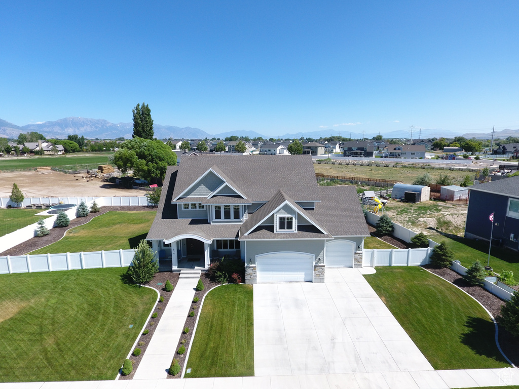 View of front of house with a garage, a front lawn, and a mountain view