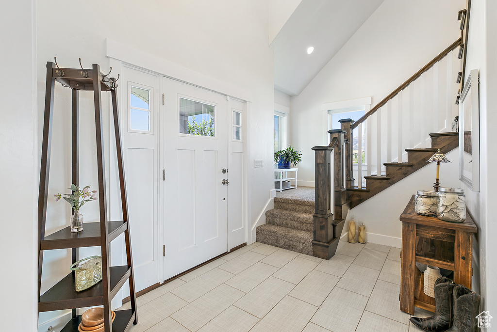Entryway with plenty of natural light, light tile flooring, and high vaulted ceiling