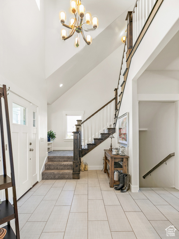 Foyer entrance with light tile flooring, an inviting chandelier, and a towering ceiling