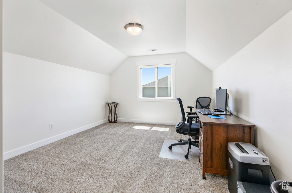 Carpeted home office featuring vaulted ceiling
