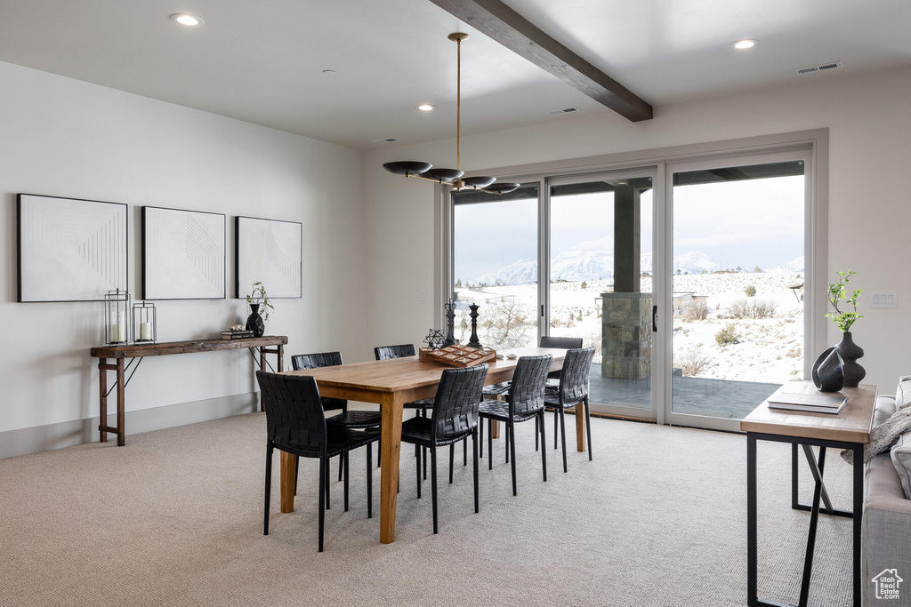 Dining area with a mountain view, beamed ceiling, light colored carpet, and a healthy amount of sunlight