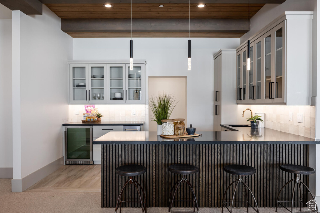 Kitchen featuring light colored carpet, kitchen peninsula, a breakfast bar, and decorative light fixtures