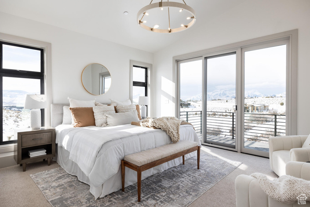 Carpeted bedroom featuring an inviting chandelier, access to outside, and a mountain view